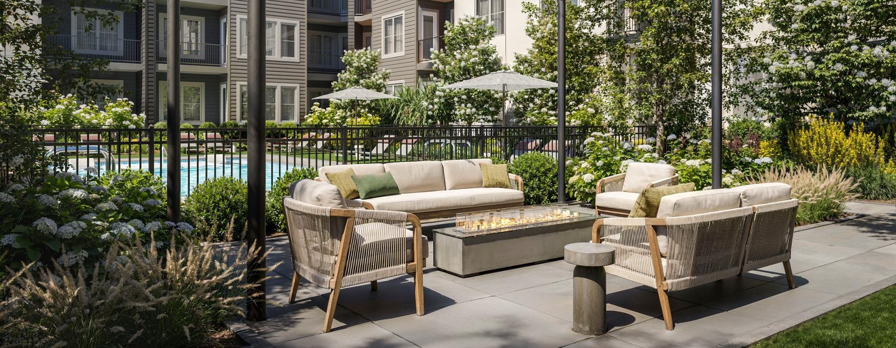 a deck with a couches and a firepit by a pool