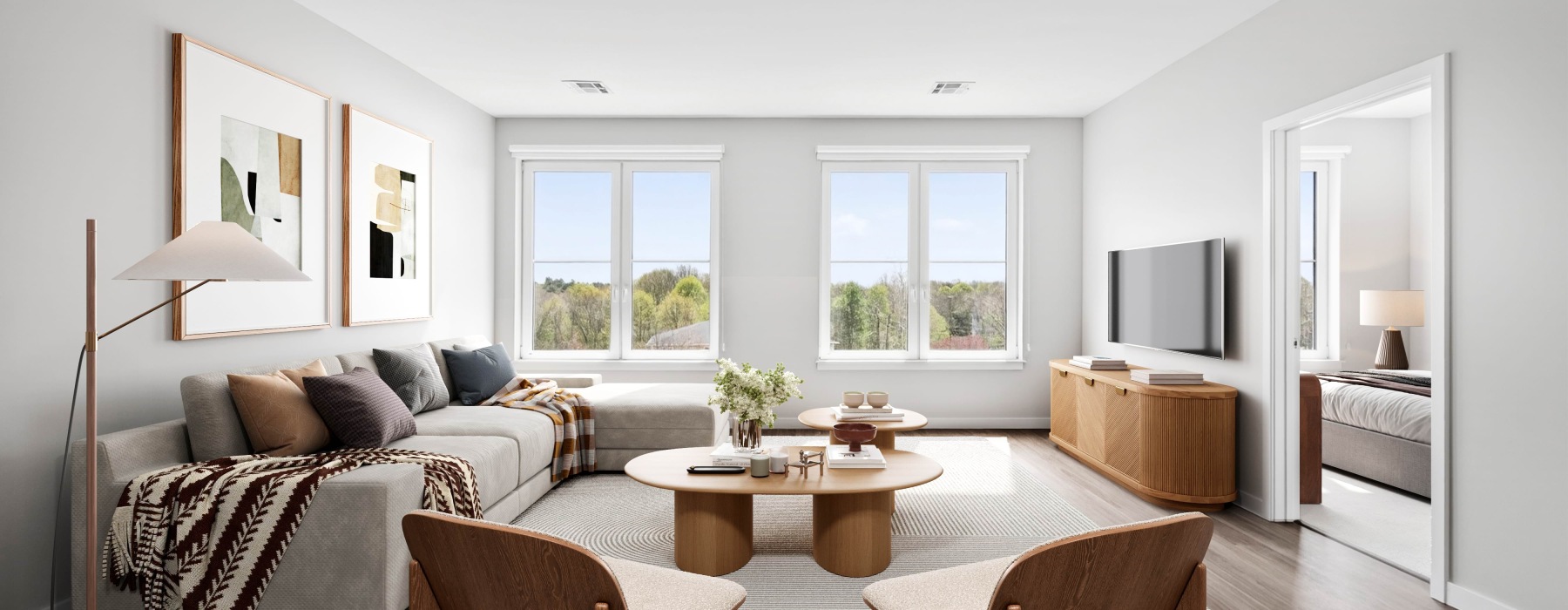 Staged oversized living room with a sectional grey couch, coffee table, two chairs, and a tv in an apartment  for rent