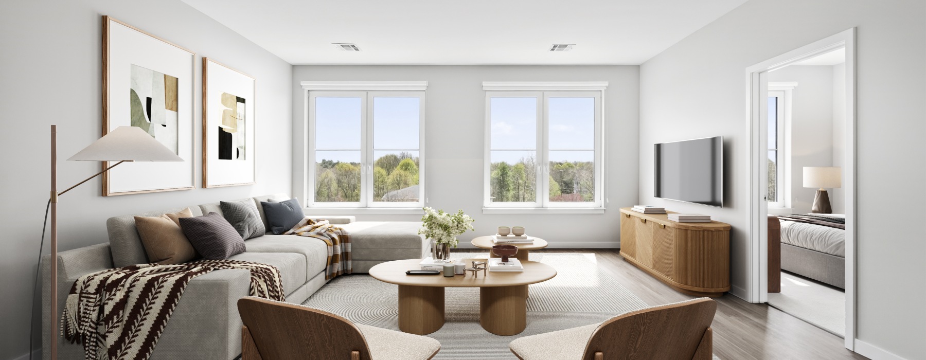 Staged oversized living room with a sectional grey couch, coffee table, two chairs, and a tv in an apartment  for rent